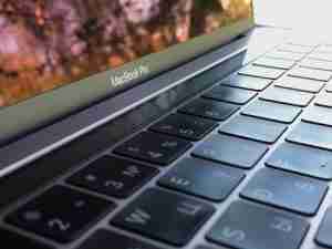 Close-up of a MacBook Pro keyboard with the screen angled, displaying the MacBook Pro logo on the hinge.